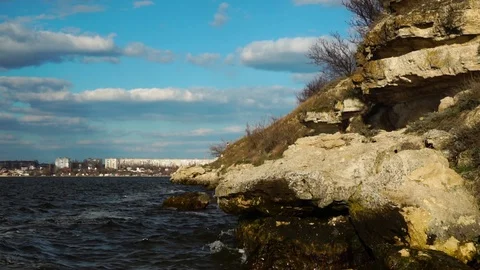Steady time lapse skyline view on river waves splashing on rock stone beach as Stock Footage 107332289