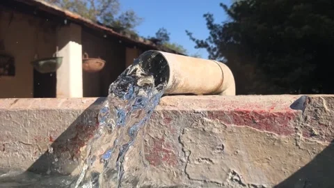 Steady water flow from an irrigation pipe flooding a rural farm land Stock Footage 328908164