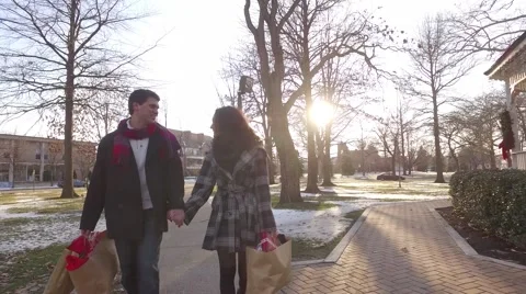 Steadycam shot of attractive young couple walking past a gazebo at  Christmas Stock Footage 59192351