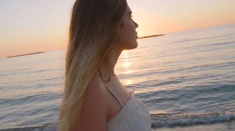 SteadyCam shot of a beautiful woman walking on the beach at sunset Stock Footage 59337910