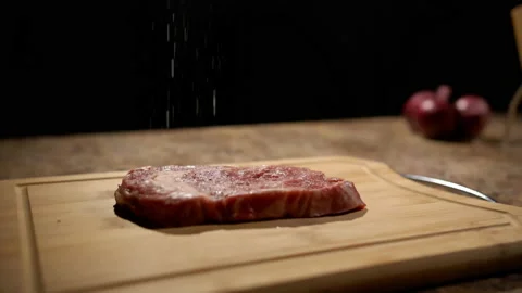 Steak being salted in dimly lit kitchen (Dolly) (Slowmo) Stock Footage 162678296