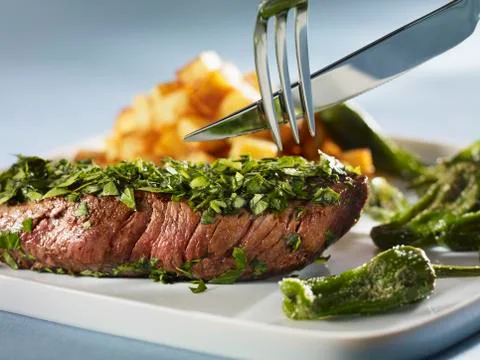 Steak coated in herbs with Pimientos de Padron Stock Photos