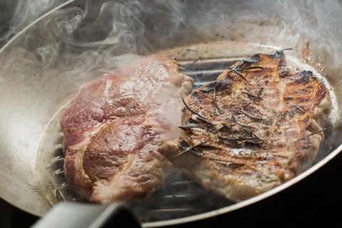 Steak cooking on grille pan. Fresh, delicious, spicy meat on a kitchen with copy Stock Photos