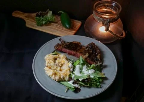 Steak dinner with mashed potatoes, salad, candlelight Stock Photos