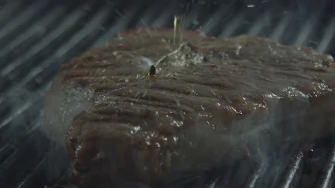 The steak falls down on a frying surface.Close-up shot. There is much steam. A Stock Footage 128830157