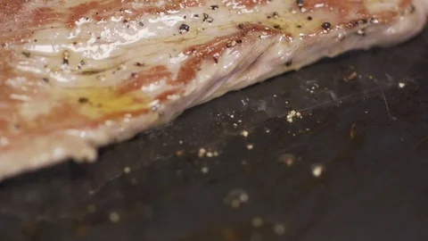 Steak filet being cooked and seasoned on a cooking plate macro shot Stock Footage 128823309