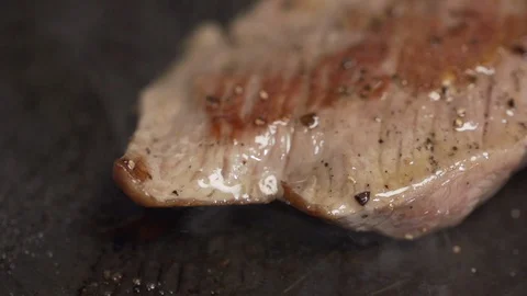 Steak filet being cooked and seasoned on a cooking plate macro shot Stock Footage 128823596