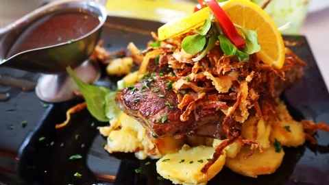 Steak with fried onions fried potatoes and sauce on a plate Stock Footage 118848920
