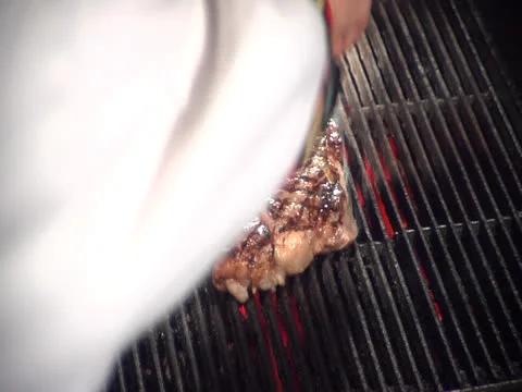 Steak on grill getting splashed with flaming butter oil, static Video stock 26191626