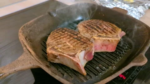 Steak is grilled in frying pan. Appetizing beef in the process of cooking Stock Footage 193993567