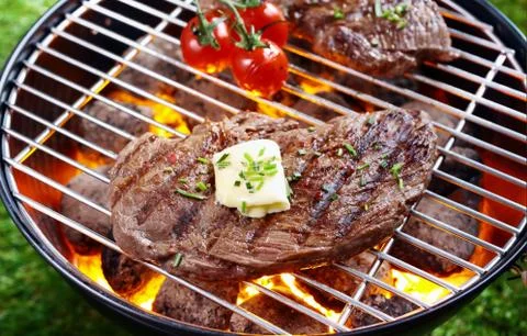 Steak grilling over a glowing fire Stock Photos