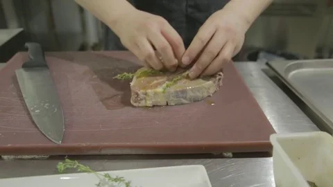 The steak lies on the table, and the chef adds seasoning Stock Footage 81423420