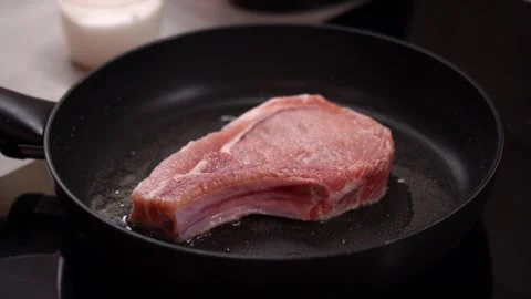 Steak, meat on bone cooked in frying pan, hisses oil, time-lapse Vidéo 232892585