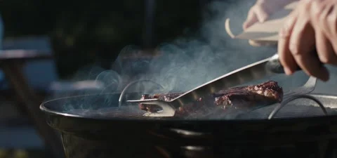 Steak put from grill on plate fork spatula in hand close up bbq smoke Stock Footage 162668559
