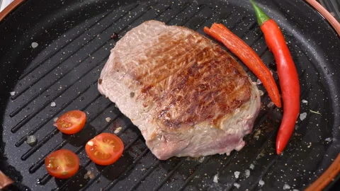 Steak with tomato fried in a pan Видео 103345958