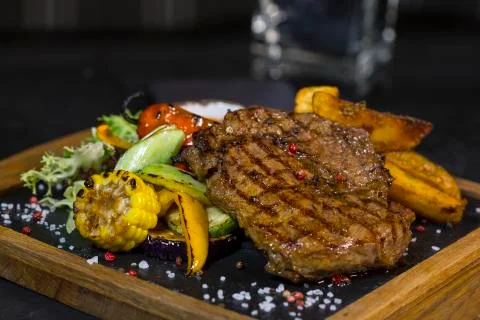 Steak with vegetables. Medium roast meat steak from pork, beef on the board Stock Photos