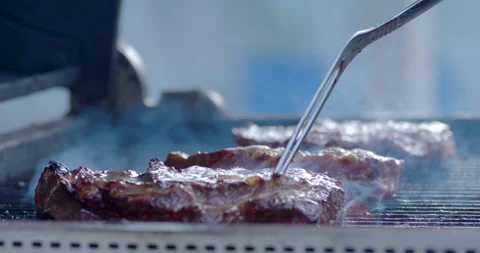 Steaks cooking on the grill getting flipped over Stock Footage 134404343