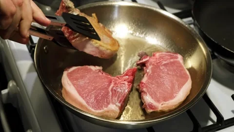 Steaks cooking, in kitchen, with frying pan, stove, tongs, spatula, with metal Stock Footage 338323808