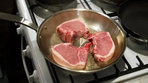 Steaks cooking in a pan on a kitchen stove with neutral mood and top-down view Stock Footage 338323839