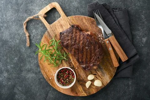 Steaks. Grilled New York Steak with spices rosemary and pepper on black marbl Stock Photos