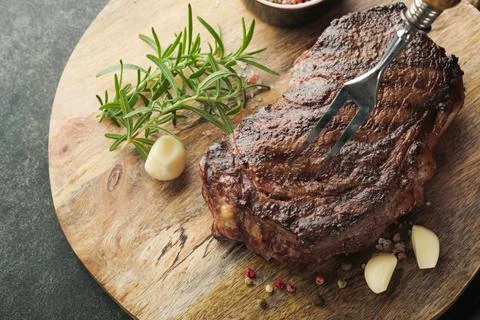 Steaks. Grilled New York Steak with spices rosemary and pepper on black marbl Stock Photos
