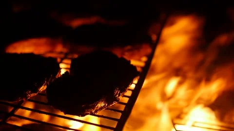 Steaks grilling over the barbecue fire in close up Video stock 153520778