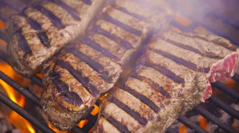 Steaks grilling over hot flames Stock Footage 22512663