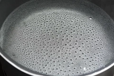 Steam bubbles at the bottom surface of the pan with boiling water Stock Photos