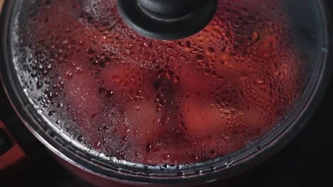 Steam builds up on the surface of a pot lid as food cooks inside. The kitchen is 库存影片 344667313