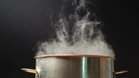 Steam comes out of the pan during cooking. Boiling water in pan on a black Stock Footage 138944760