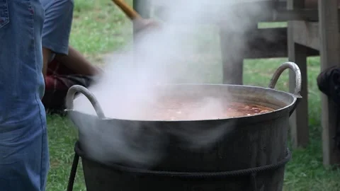 Steam coming out of the cauldron in which pieces of meat and potatoes are bo Stock Footage 145636718