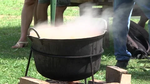 Steam coming out of the cauldron in which pieces of meat and potatoes are bo Stock Footage 145655982