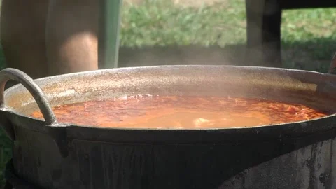 Steam coming out of the cauldron in which pieces of meat and potatoes are bo Stock Footage 145663473