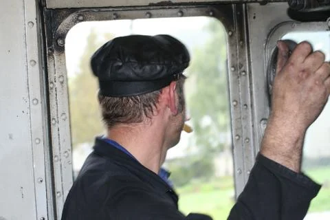 Steam engine driver looking out of window and smoking cigarette Stockfoto's