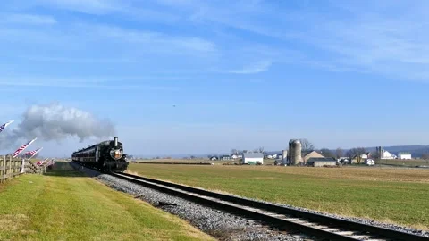 Steam Engine Trains Pass Through Fields and Farms in Bright Blue Sky on a S.. Stock Footage 337642905