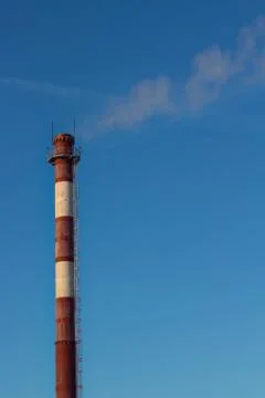 Steam escaping from pipe on the sky background at sunset, industrial emissions Stock Photos