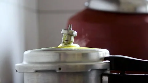 Steam escaping from pressure cooker while cooking on kitchen stove close up Stock Footage 341837887