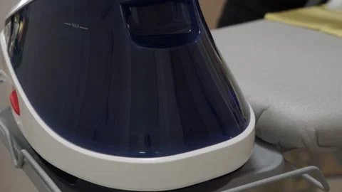 The steam generator base unit heats water on the ironing board stand. Stock Footage 320890170