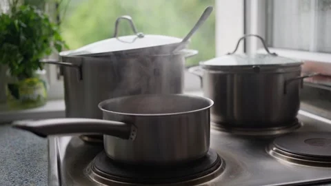 Steam gently rises from pots as they boil on the stove a fresh kitchen setting Stock Footage 295551957