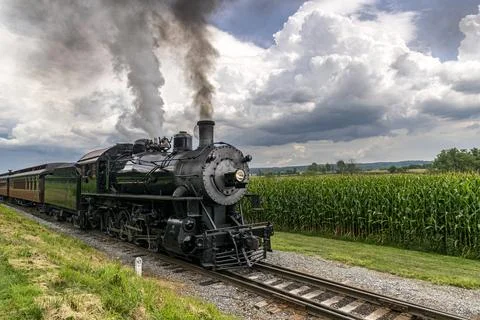 Steam Passenger Train Passing Corn Fields and Blowing Smoke on a Sunny Summer Stock Photos