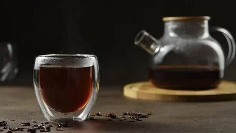Steam rises above cascara infusion as condensation coats glass rim with teapot Stock Footage 346586198