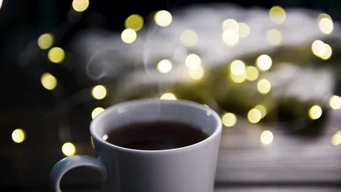 Steam rises from a cup of tea against the background of a garland. Stock Footage 146984677