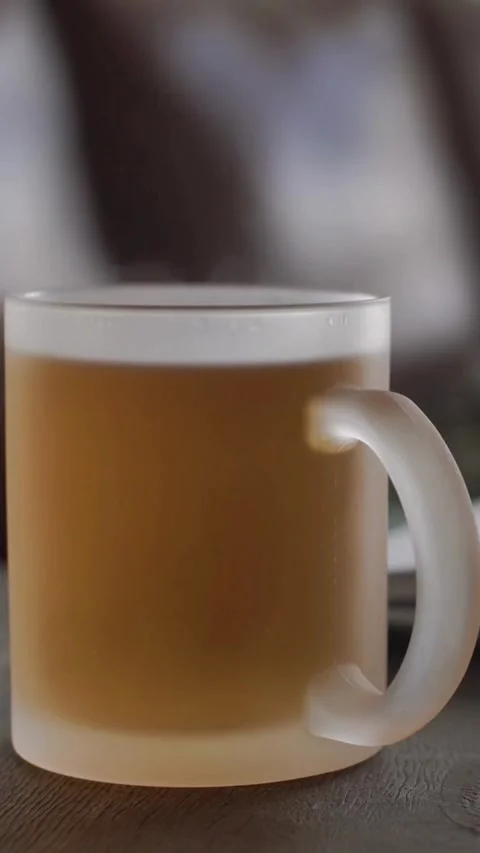 Steam rises from hot amber liquid in frosted mug Stock Footage 334168861