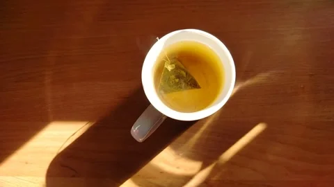 Steam rises from a mug of hot tea in the morning in the warm sun. Stock Footage 308574810
