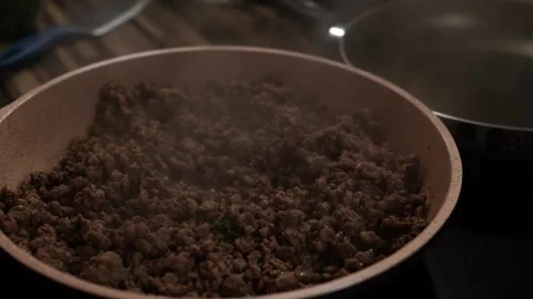 Steam rises over minced meat simmering in oil in a frying pan Video stock 269158679