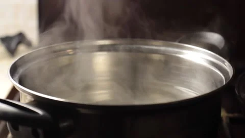 Steam rises from a pan with water close-up, blurred background Stock Footage 133250984