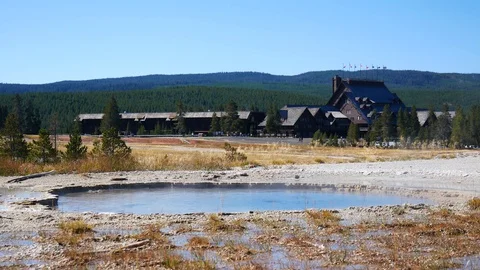Steam Rising from a Hot Spring With Old Faithful Lodge in Background Stock Footage 128036104