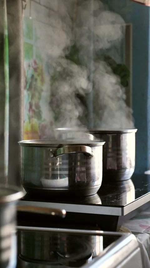 Steam rising from multiple pots boiling on a kitchen stove. Stock Footage 342024982