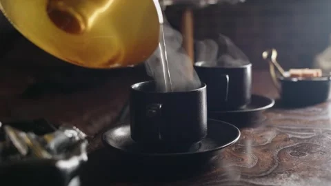 Steam rising over black ceramic cup while pouring from glass kettle Video stock 331885018