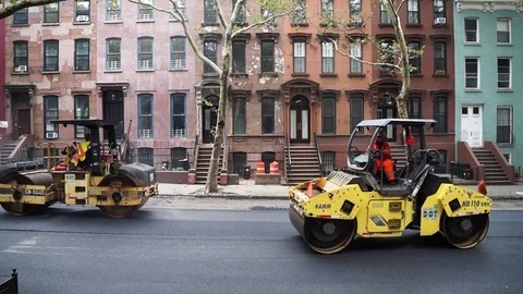 Steam rollers and compactors criss crossing while paving a residential street Stock Footage 80206602